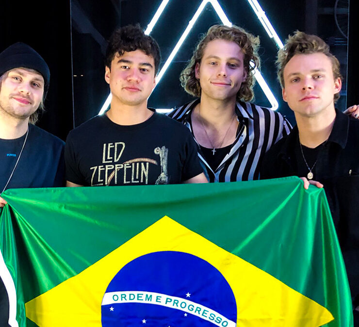 Integrantes do 5 Seconds of Summer segurando a bandeira do Brasil